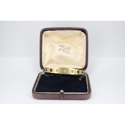 38 - An early 20th century ruby and diamond hinged bangle. Tests 8/9ct. Weight 11.70 grams(To Note: Viewi... 