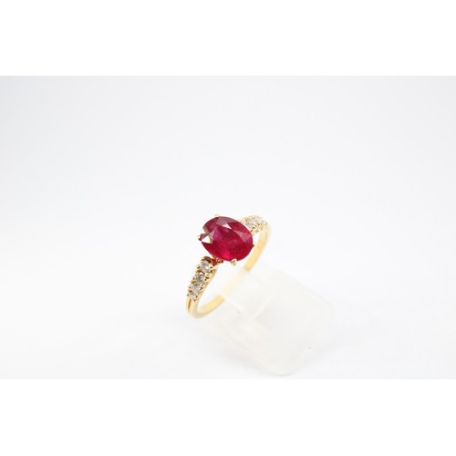61 - An oval ruby and graduated brilliant cut diamond ring. Stamped 750. Size Q 1/2. Weight 3.23 grams