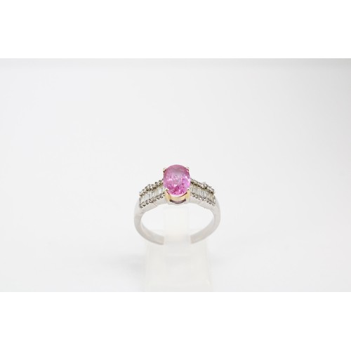 63 - An oval pink sapphire dress ring with baguette and brilliant cut diamonds to each shoulder. Stamped ... 