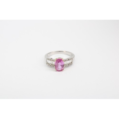 63 - An oval pink sapphire dress ring with baguette and brilliant cut diamonds to each shoulder. Stamped ... 