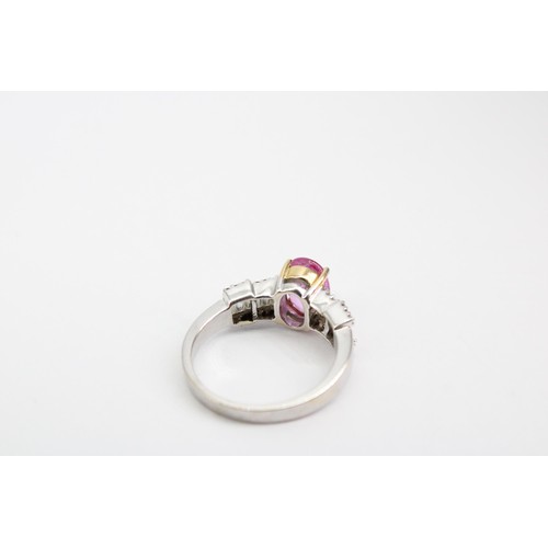 63 - An oval pink sapphire dress ring with baguette and brilliant cut diamonds to each shoulder. Stamped ... 