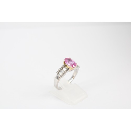 63 - An oval pink sapphire dress ring with baguette and brilliant cut diamonds to each shoulder. Stamped ... 
