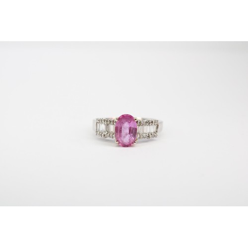 63 - An oval pink sapphire dress ring with baguette and brilliant cut diamonds to each shoulder. Stamped ... 