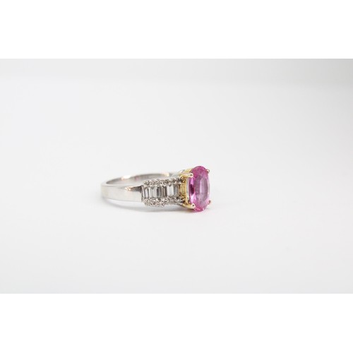 63 - An oval pink sapphire dress ring with baguette and brilliant cut diamonds to each shoulder. Stamped ... 