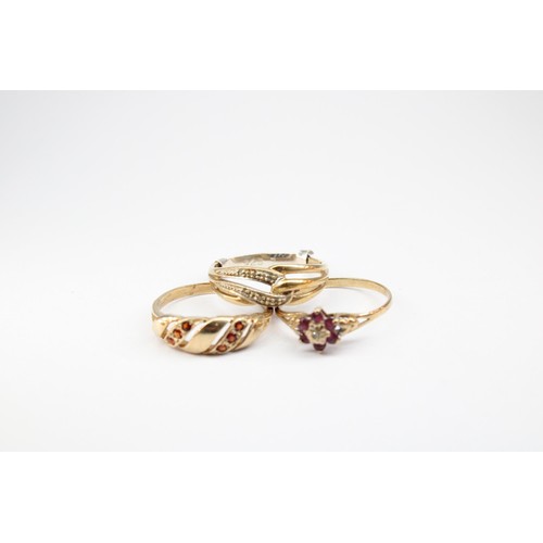67 - A group of three rings with marks or testing as 9ct gold. To include a ruby and diamond cluster, Siz... 