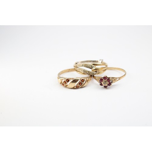 67 - A group of three rings with marks or testing as 9ct gold. To include a ruby and diamond cluster, Siz... 