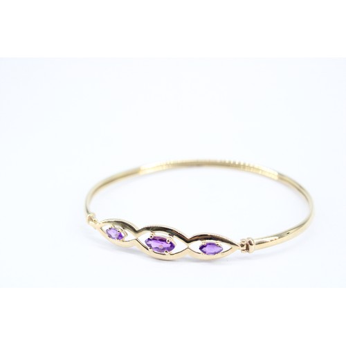 170 - A 14ct Tested Bangle, Featuring Three Central Marqu&eacute;s Cut Amethyst set within oval pierced pa... 