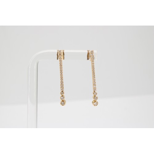 35 - A pair of graduated brilliant cut diamond line ear pendants. Length 32mm. Stamped 14ct. Weight 2.22 ... 