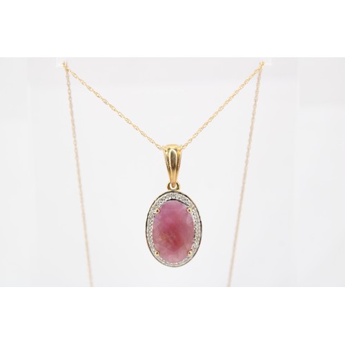 41 - An oval ruby and diamond cluster pendant. Length 27mm. Suspended from a fine link chain. Stamped 14k... 