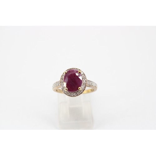 52 - An oval ruby and diamond cluster ring. Stamped 10K. Size N 1/2. Weight 3.93 grams