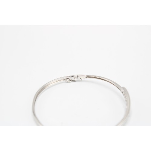  A 9ct White Gold Bangle, With a Central Princess Cut Blue Stone Bypass Section of Five Graduating St... 