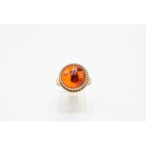31 - An 8ct gold and amber ring, marked 333, cabochon cut, rope twist border, size P, weight 3.38g