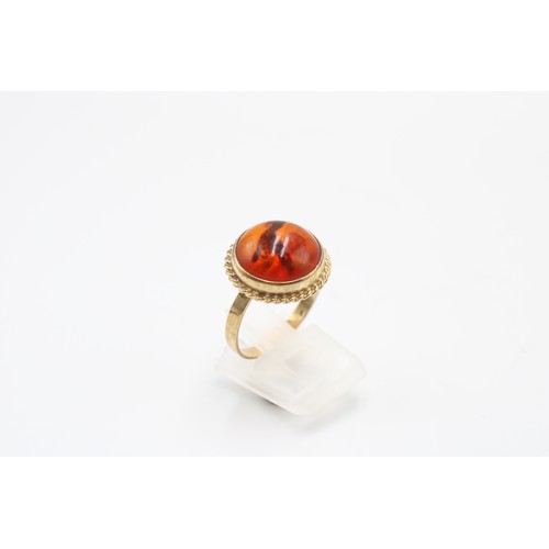 31 - An 8ct gold and amber ring, marked 333, cabochon cut, rope twist border, size P, weight 3.38g