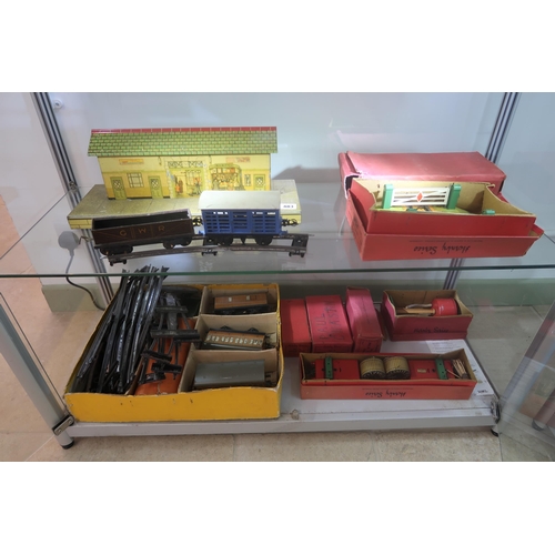 483 - A Hornby tinplate railway and station, O-Gauge, including the locomotive (damaged), railcars, some o... 