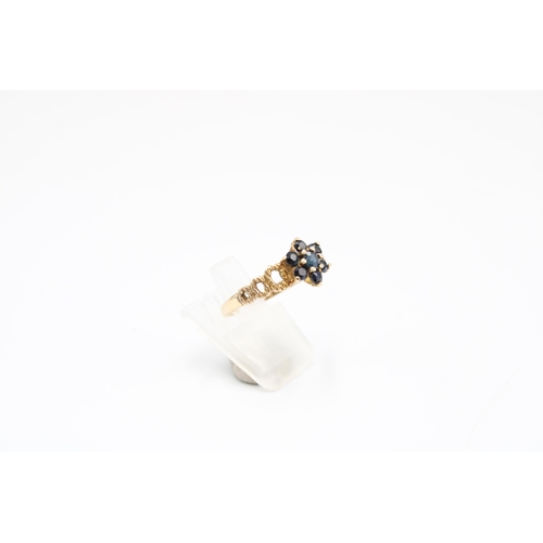  A 9ct gold and sapphire cluster ring, set with seven round cut stones within openwork shoulders, gro... 