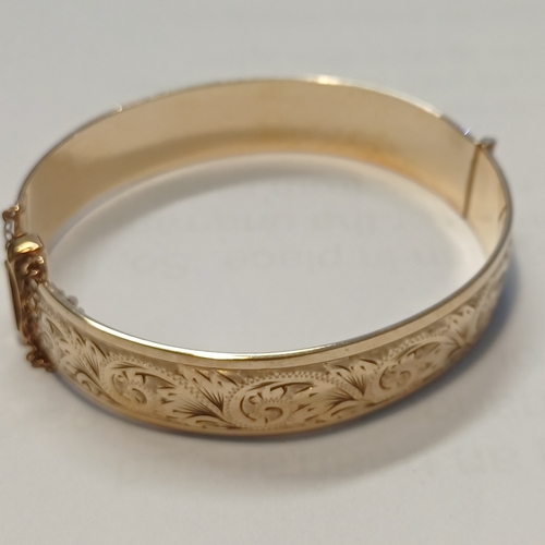 235 - A One Fifth 9ct Gold Bangle with decoration one side and safety chain