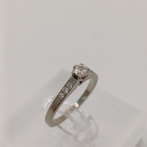 24 - A Solitaire Diamond Ring with three small diamonds set into the shoulder of the shank each side
- 18... 