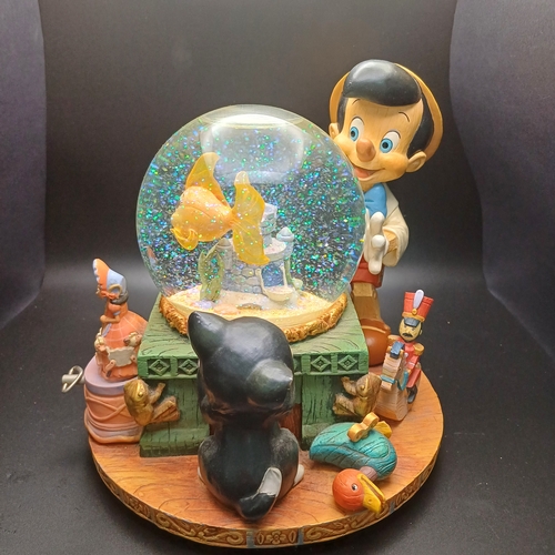 102 - Disney Snow Globe with Pinocchio looking into the globe where the fish in side rotas when you wind t... 