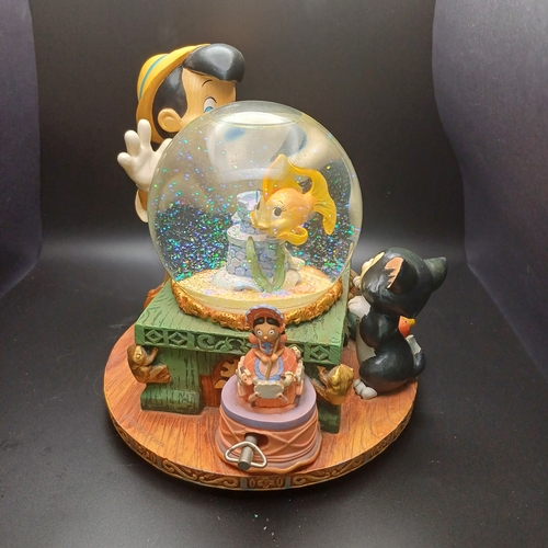 102 - Disney Snow Globe with Pinocchio looking into the globe where the fish in side rotas when you wind t... 