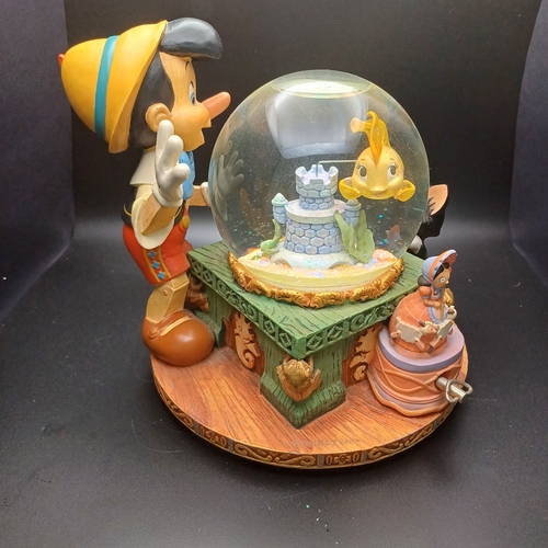 102 - Disney Snow Globe with Pinocchio looking into the globe where the fish in side rotas when you wind t... 