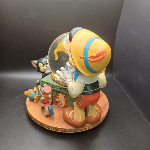 102 - Disney Snow Globe with Pinocchio looking into the globe where the fish in side rotas when you wind t... 