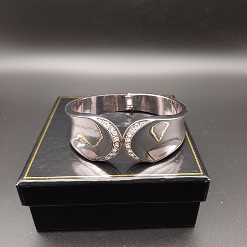 83 - In original box we have a stunning heavy silver coloured metal sprung hing bangle with white stone s... 