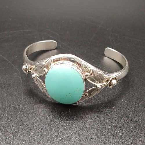 27 - Silver Bangle with Large Turquoise Stone inset with silver flower detail on the sides.    
- 925 Sil... 