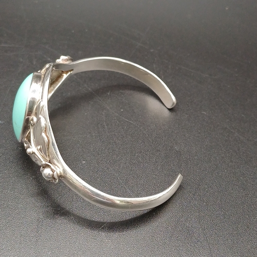 27 - Silver Bangle with Large Turquoise Stone inset with silver flower detail on the sides.    
- 925 Sil... 
