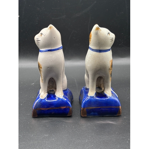 115 - This is a pair of Staffordshire pottery cat figurines seated on blue cushions. These items are colle... 