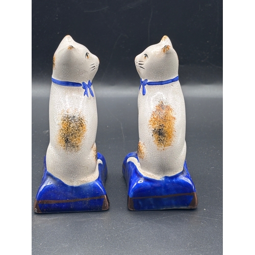 115 - This is a pair of Staffordshire pottery cat figurines seated on blue cushions. These items are colle... 
