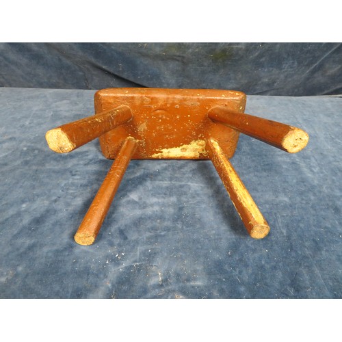 616 - A country made miniature stool on four legs with brown paintwork, measuring 18cm tall.