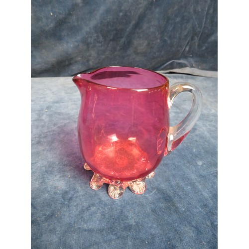 622 - Four pieces of cranberry glass being small heart shaped dish on shell style feet, cream jug on shell... 