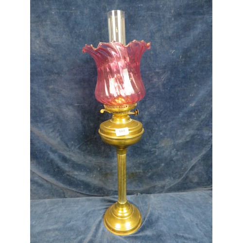 664 - A brass pedestal oil lamp with chimney and cranberry glass shade.