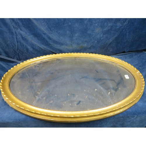 682 - A large oval mirror in heavy gilt frame 99cm x 71cm.