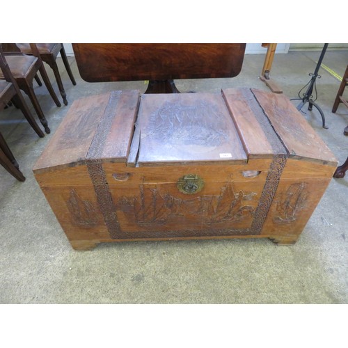 747 - A carved Far Eastern wooden coffer with decorative panels.