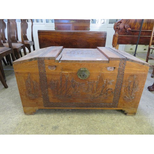 747 - A carved Far Eastern wooden coffer with decorative panels.