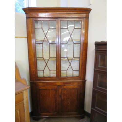 758 - An antique oak corner cupboard with glazed doors and 2 shelves and cupboard under on bracket feet wi... 