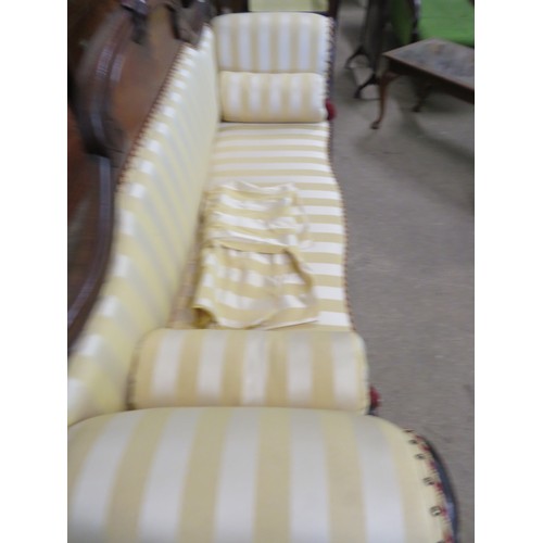 778 - An antique mahogany sofa with carved decoration and scroll arms upholstered in gold striped material... 