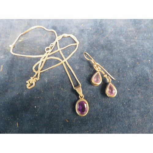 693 - A white metal pendant and chain set with an amethyst stone and a matching pair of drop earrings.