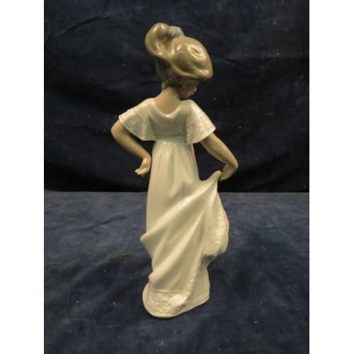 697 - A Nao figurine of a girl dressed in white standing in a curtsey pose.