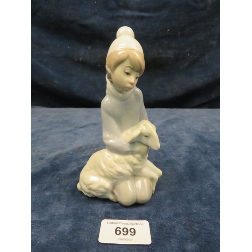 699 - A Lladro figurine of a boy with a lamb on his knees.