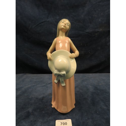 700 - A Lladro figurine of a girl wearing a pink dress and holding a hat.