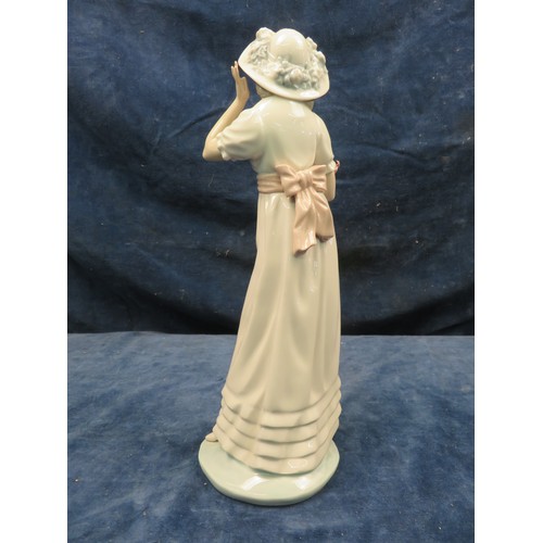 702 - A Nao figurine of a lady holding a sheath of lilies.