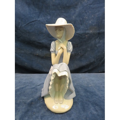 704 - A Nao figurine of a lady wearing a summer hat and seated on a wall.