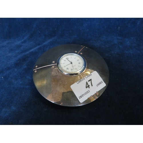 47 - An unusual desktop clock with quartz movement in weighted silver-plated case.