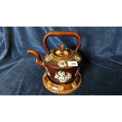 498 - A bargeware teapot and stand being brown glazed with decorative floral applied decoration.