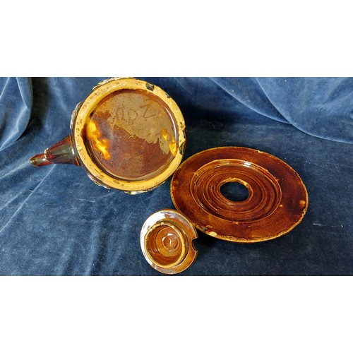 498 - A bargeware teapot and stand being brown glazed with decorative floral applied decoration.