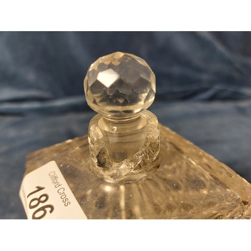 186 - A cut glass scent bottle with glass stopper and silver top, marks worn, big chip to rim of bottle.