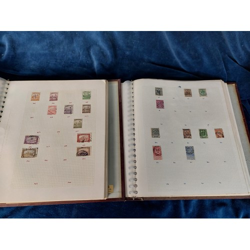 312 - Two maroon folders containing a quantity of stamps from around the world.