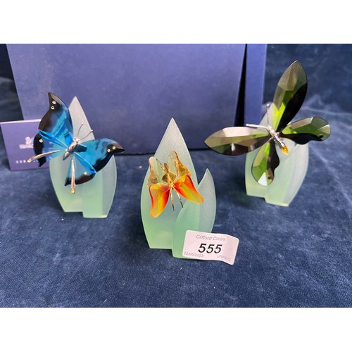 555 - Three Swarovski Crystal figures of Butterflies on purpose made stands, with original box.